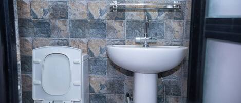 Une salle de bain avec des toilettes, un lavabo et des murs carrelés.
