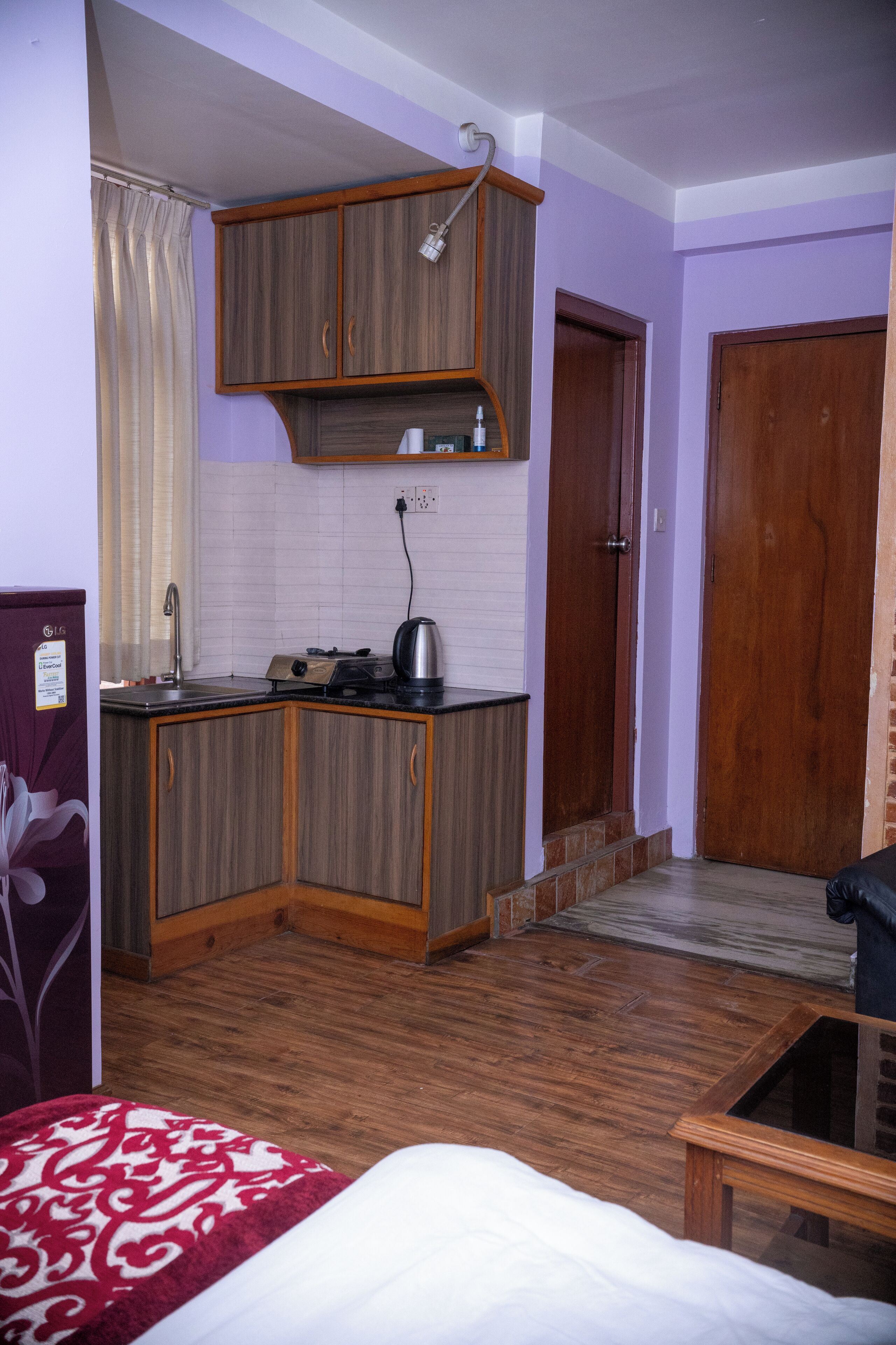 A compact room with a kitchenette, a bed, and a wooden door.