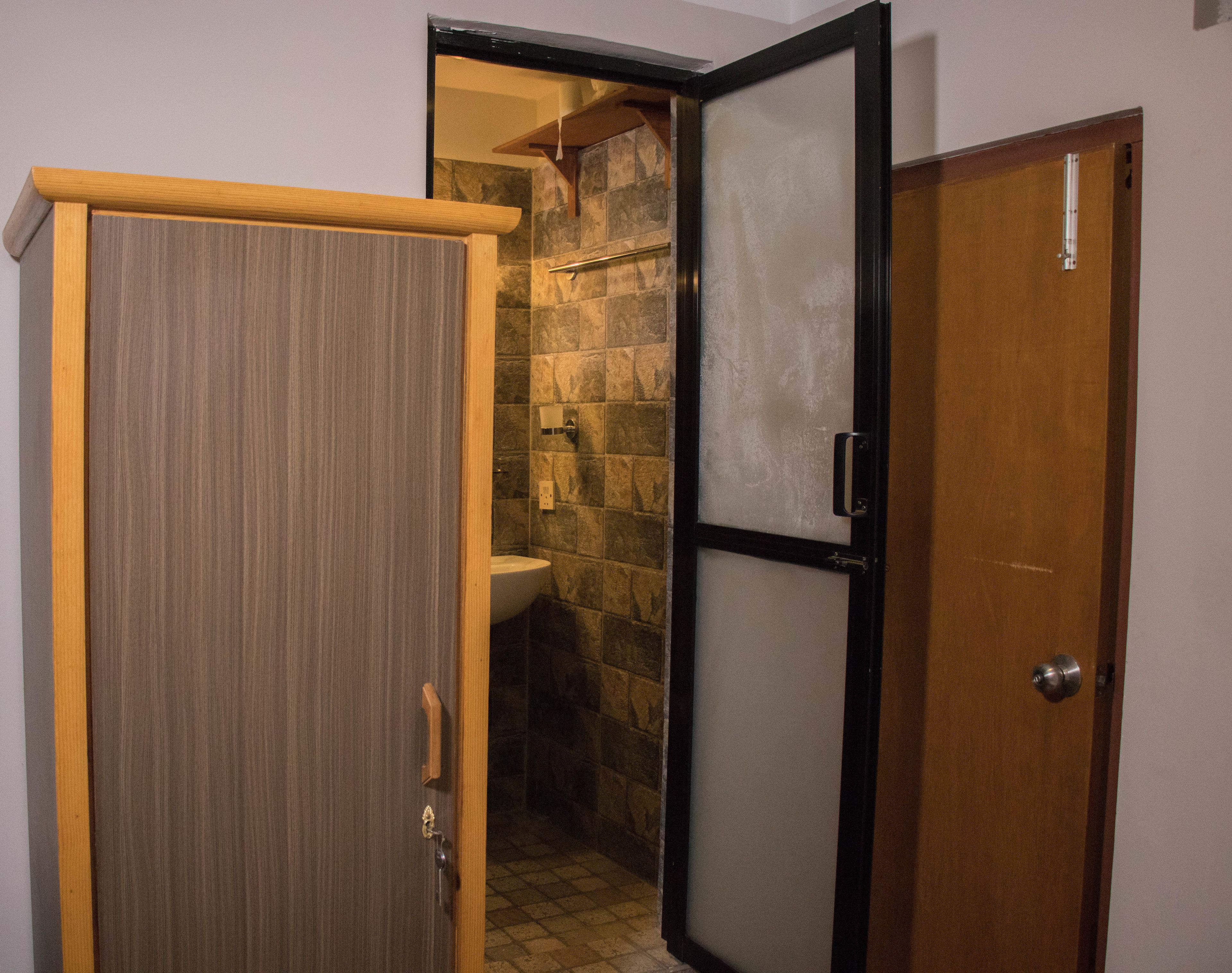 Ein Badezimmer mit Holztür, Duschkabine aus Glas und einer Steinwand.