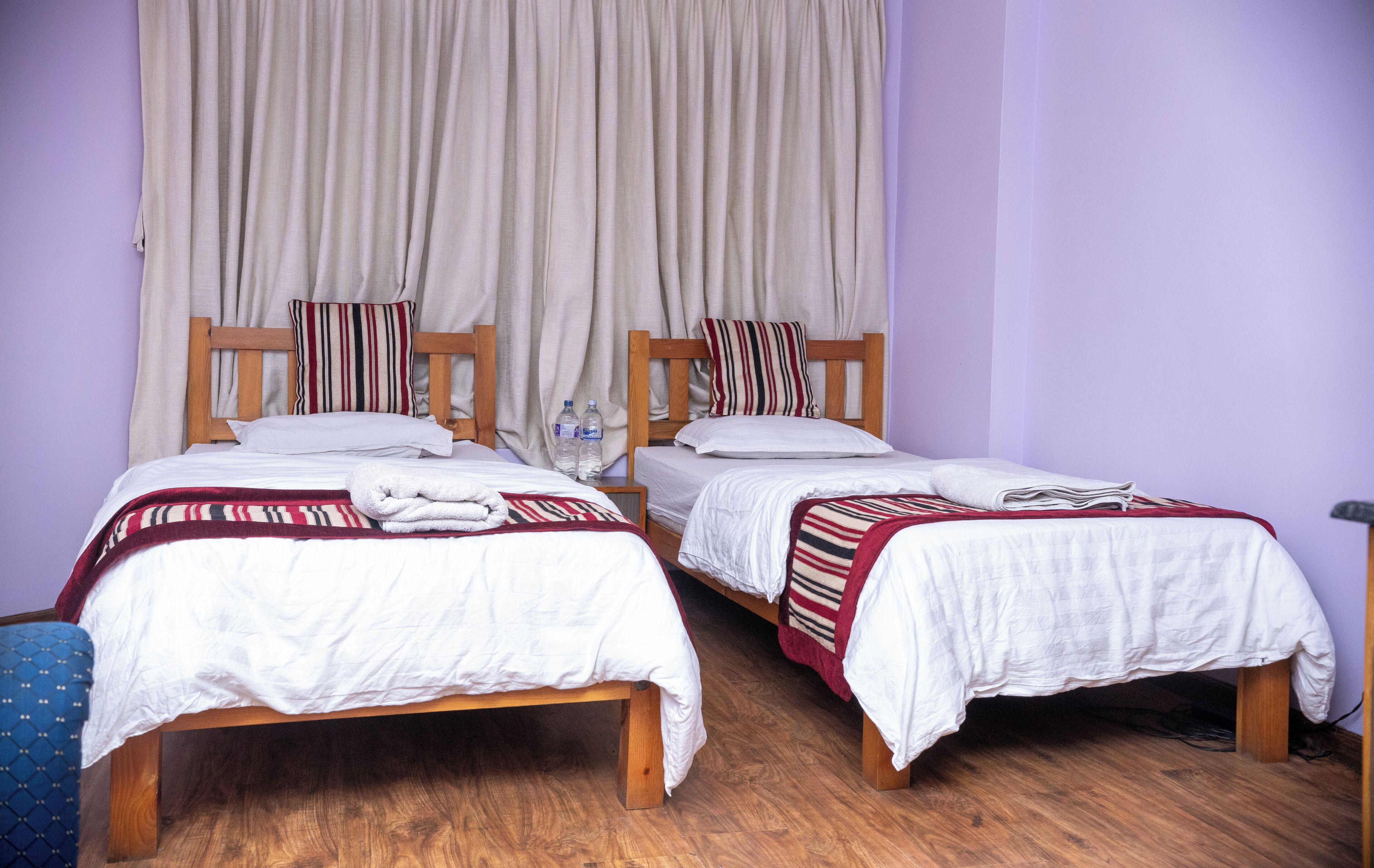 Two single beds with wooden frames, white bedding, and striped blankets.
