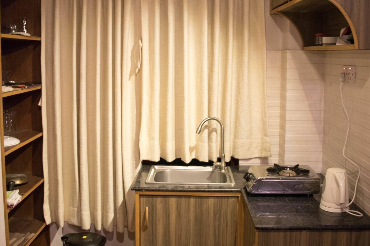 Uma cozinha compacta com uma pia, uma chaleira e um pequeno balcão.