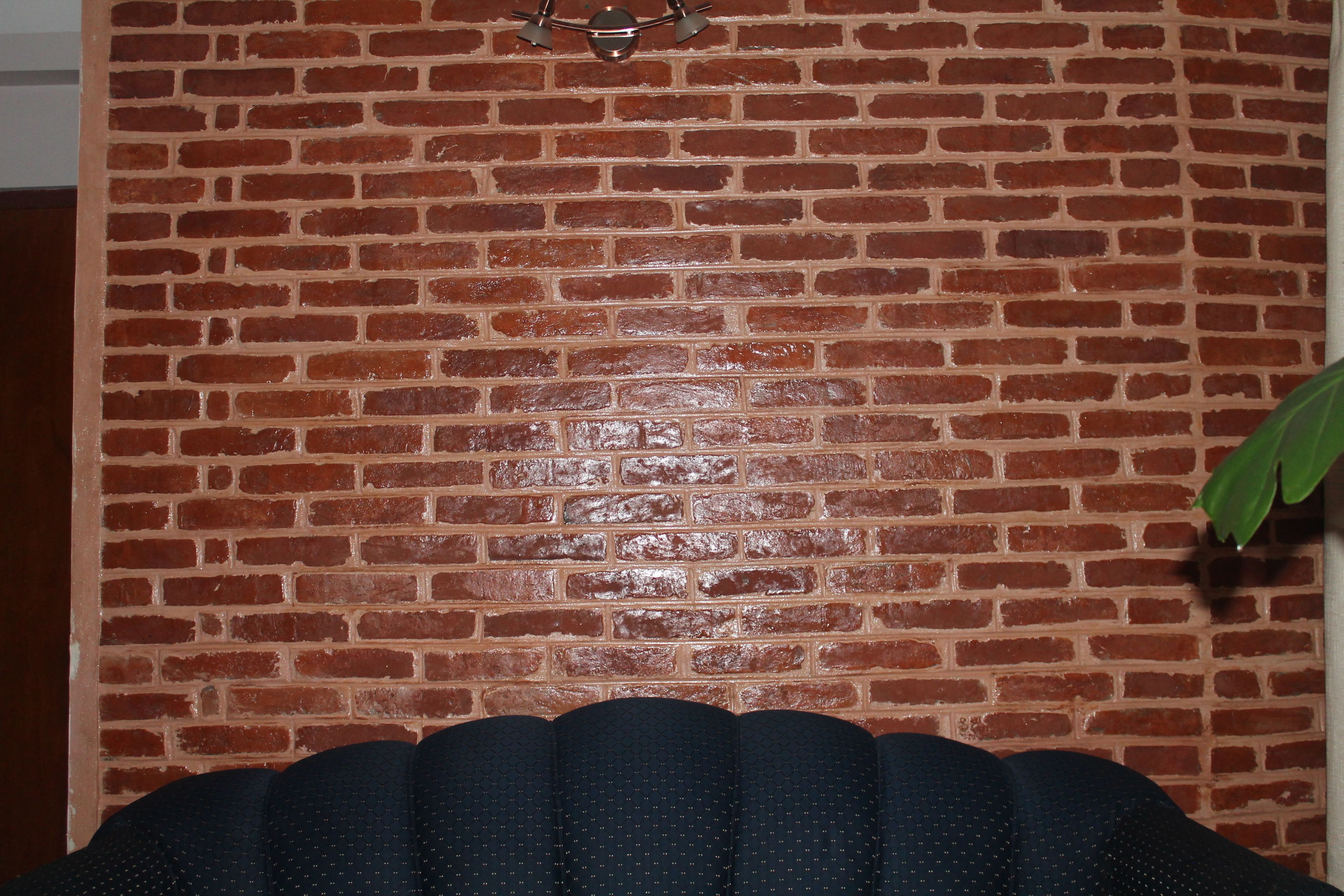 Pared de ladrillo con un accesorio metálico y una planta.