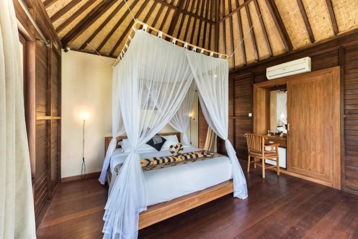 A room with a four-poster bed, wooden walls, a desk, and a chair.