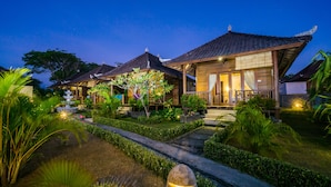 A traditional wooden house with a tiled roof, surrounded by lush greenery and a well-maintained garden. - Bali Belva (Lembongan Island)