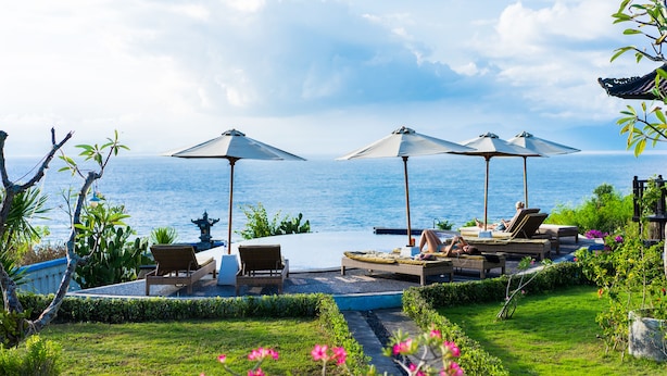 A poolside area with lounge chairs and umbrellas, overlooking a body of water. - Bali Belva (Lembongan Island)
