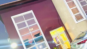 A building with a large window and a car parked in front. - Posh Apartments Metro (Lagos)