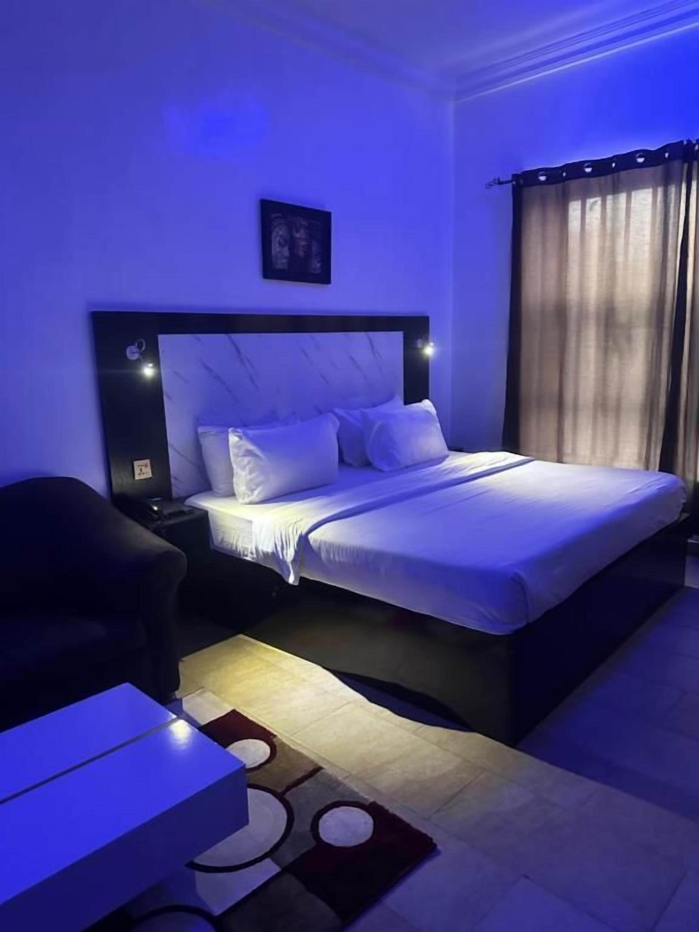 Een slaapkamer met een bed, nachtkastjes, een stoel en een bureau.