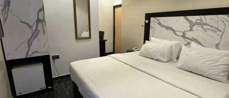 Habitación de hotel moderna con una cama grande, una pared de mármol y un cuadro enmarcado.