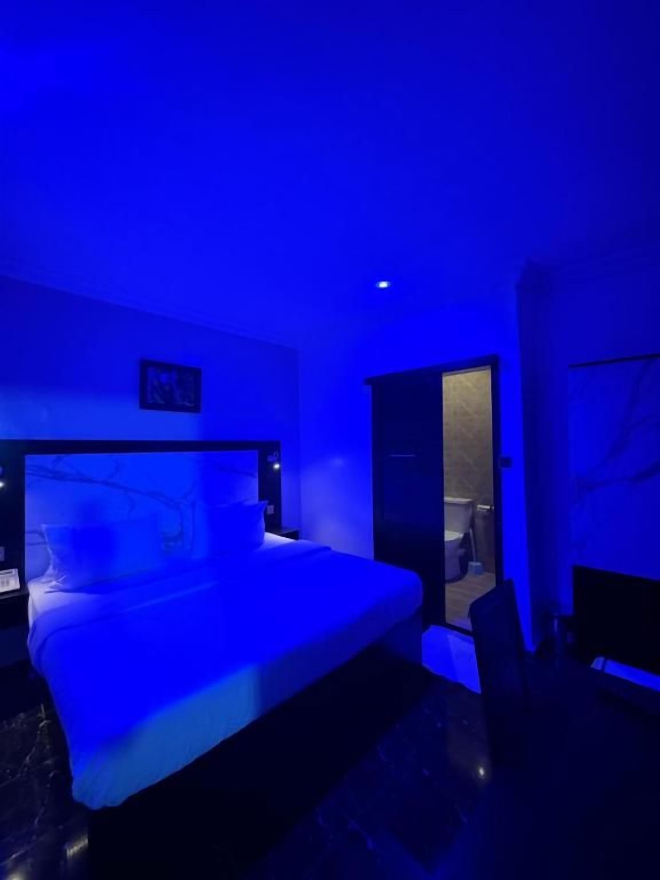 A hotel room with a bed, a nightstand, and a door leading to a bathroom.