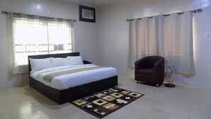 A bedroom with a bed, a chair, and a window with curtains. - Posh Apartments Metro (Lagos)