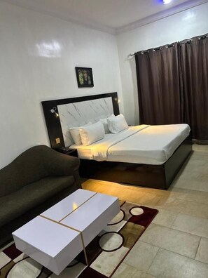 A bedroom with a bed, a sofa, and a bedside table.