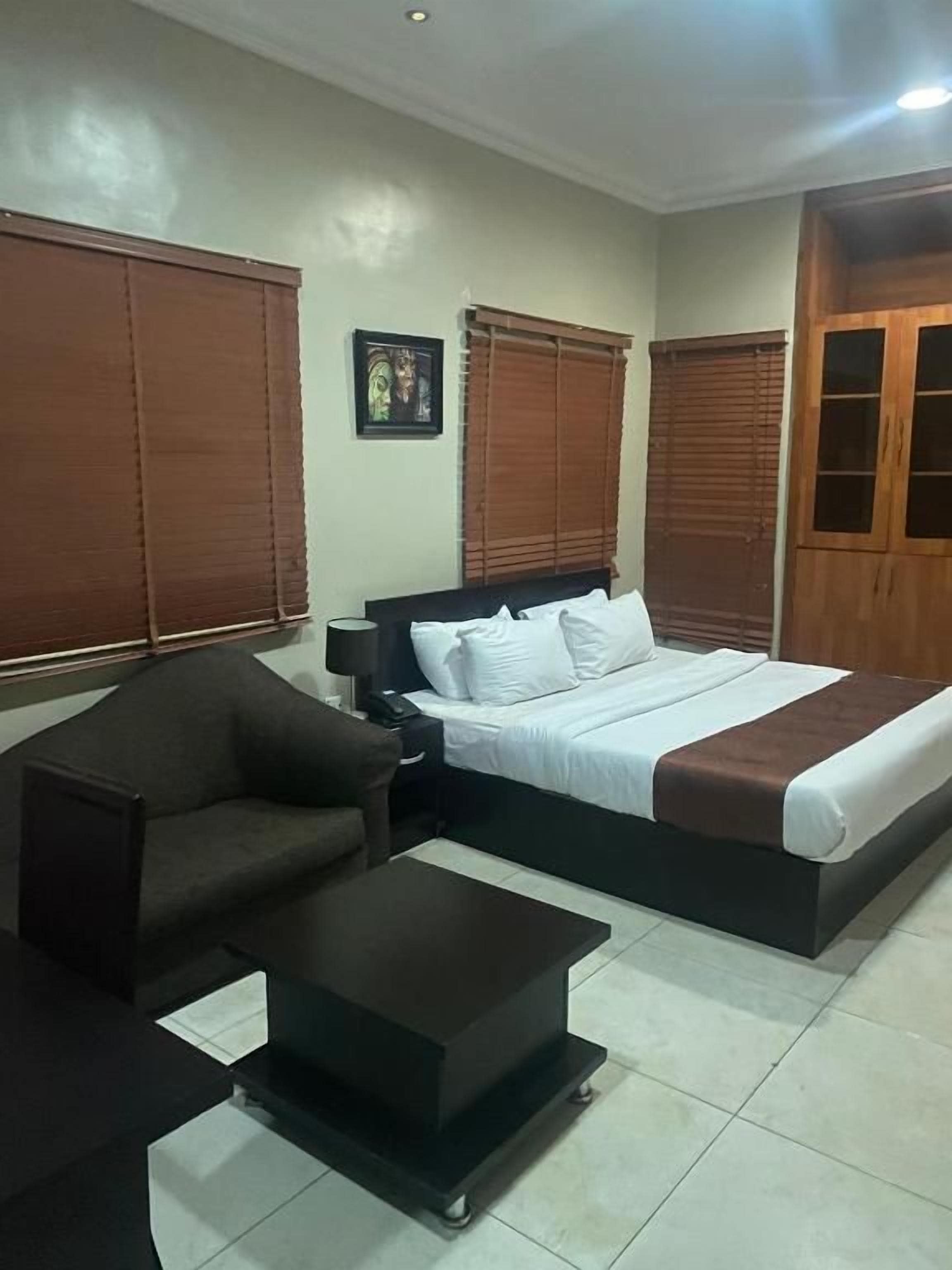 A bedroom with a bed, a sofa, a coffee table, and a wardrobe.
