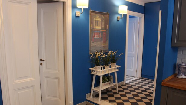 A hallway with a checkered floor, a white door, a mirror, and a small white shelf with plants. - Le Stanze di Pietro (Rome)