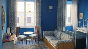 A room with a bed, a sofa, a table with chairs, and a window with curtains. - Le Stanze di Pietro (Rome)