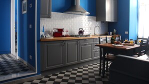 A modern kitchen with grey cabinets, a black and white checkered floor, and a dining area with a table and chairs. - Le Stanze di Pietro (Rome)