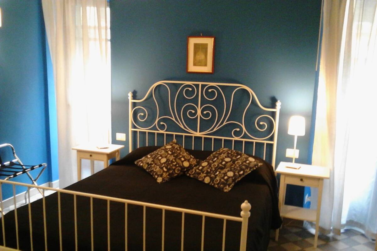 A bed with a white metal headboard, two pillows, and a framed picture on the wall.