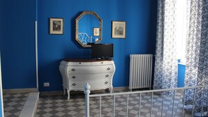 A room with blue walls, a white dresser, a mirror, and a radiator. - Le Stanze di Pietro (Rome)