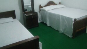 A small, clean room with a single bed, a bedside table, and a mirror. - Asix Hotel (Trincomalee)