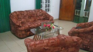 A living room with patterned sofas, a glass coffee table, and a laptop.