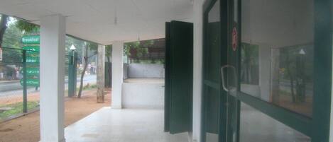 Una entrada de edificio moderna y limpia con puerta de vidrio, piso de baldosas y un camino que lleva a una zona de estar.