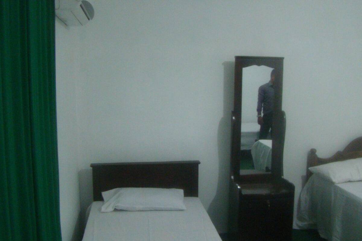 A room with two beds, a mirror, and a green curtain.