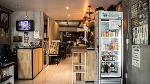 Un bar con barra, un refrigerador lleno de bebidas y un televisor mostrando un evento deportivo.
