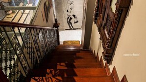 Una escalera de madera con barandales ornamentados y vistas a una habitación con un cartel grande.