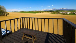 Una terraza de madera con vistas a un campo extenso y montañas lejanas.