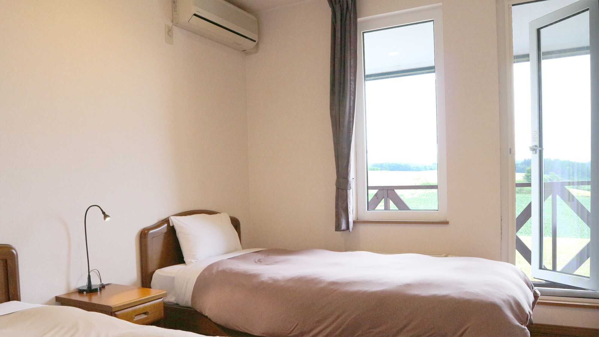 Un dormitorio con cama, mesita de noche, lámpara, aire acondicionado y ventana con vistas.