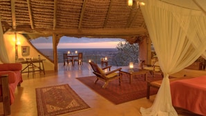 A room with a bed, a chair, a table, and a view of the landscape. - Elewana Elsa’s Kopje (Meru National Park)
