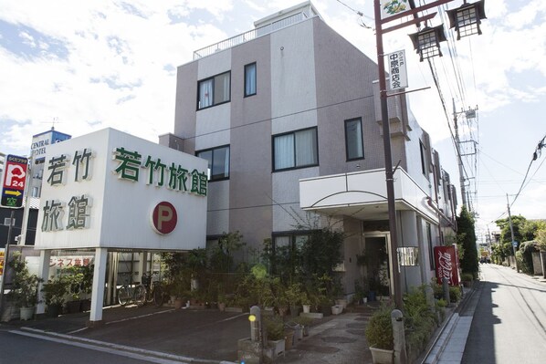 A building with a sign for a hotel and a parking lot. - Wakatake Ryokan (Kawagoe)
