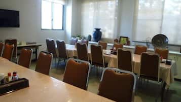 A dining area with tables and chairs, a large vase, and a window with curtains.