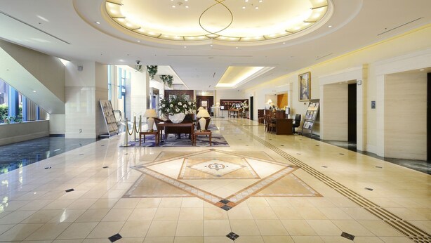 A spacious lobby with a central seating area, a reception desk, and a large decorative light fixture on the ceiling. - Viale Osaka (Osaka)