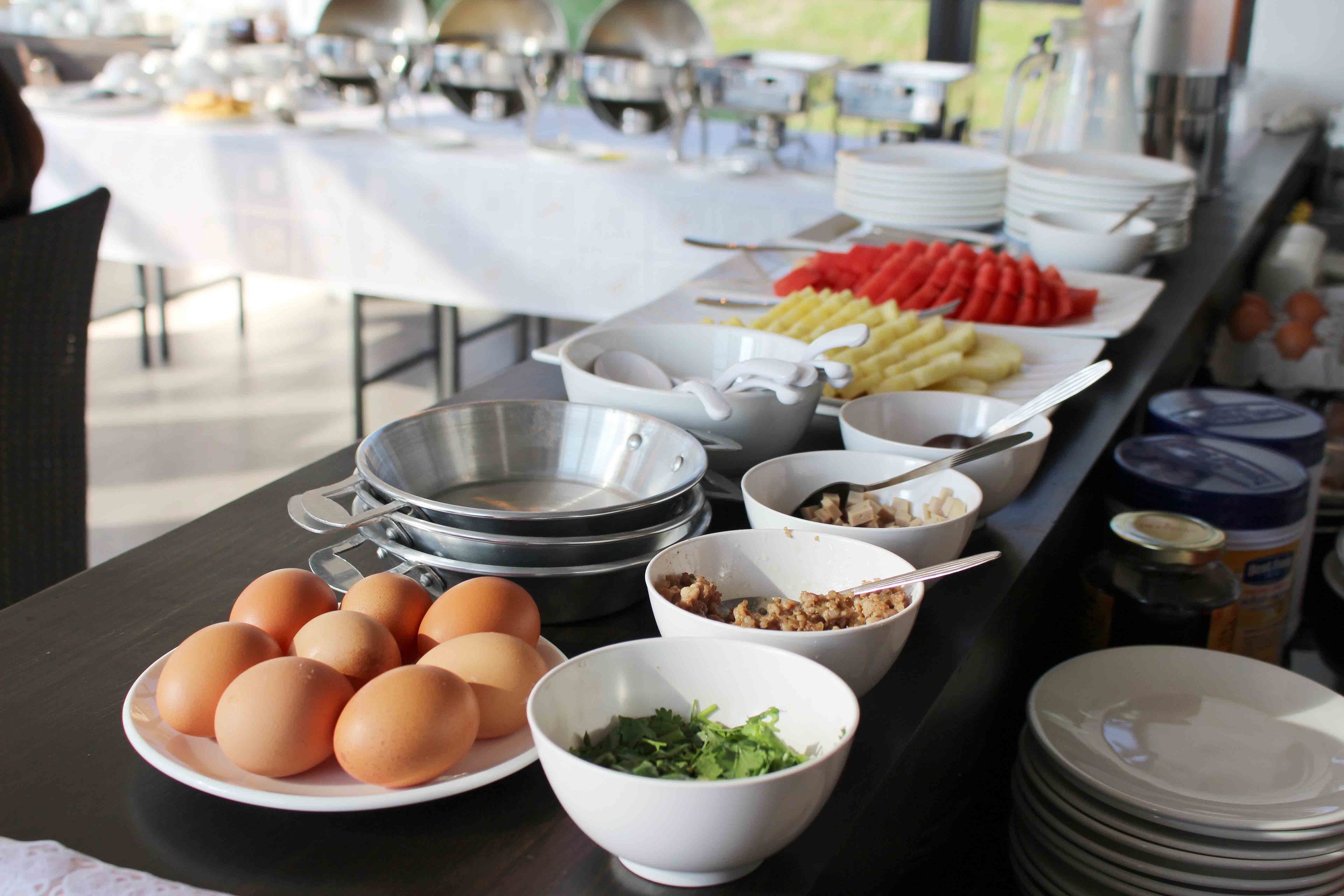 Montaje de bufé con platos de huevos, ensaladas en boles y diversas opciones de comida.