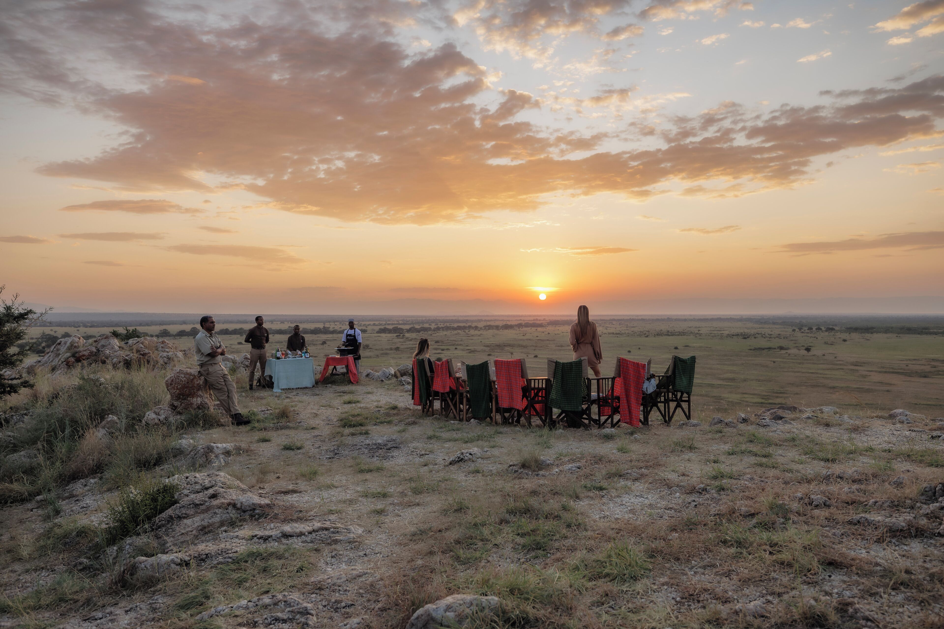 Un groupe de personnes est assis à une table, avec un coucher de soleil en arrière-plan.