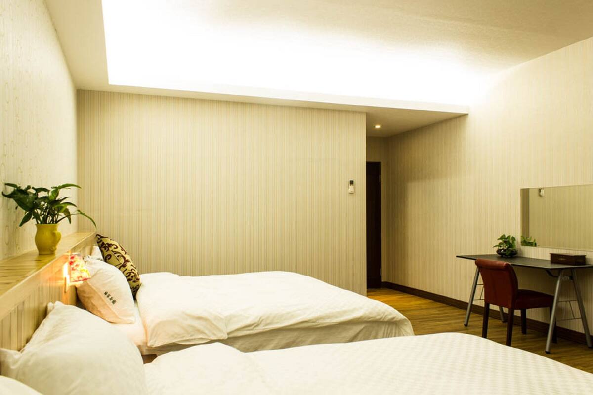 Ein Hotelzimmer mit einem Bett, einem Schreibtisch und einem Stuhl. Auf dem Schreibtisch und dem Bett stehen Pflanzen.