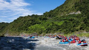 Un grupo de personas haciendo rafting en un río rodeado de colinas verdes exuberantes.