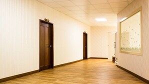Un pasillo con suelo de madera, paredes blancas y puertas.
