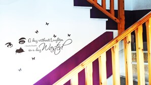 A staircase with wooden railings and a wall with a quote and butterfly decals. - Roquetas Beach & Playa Serena Golf (Roquetas de Mar)