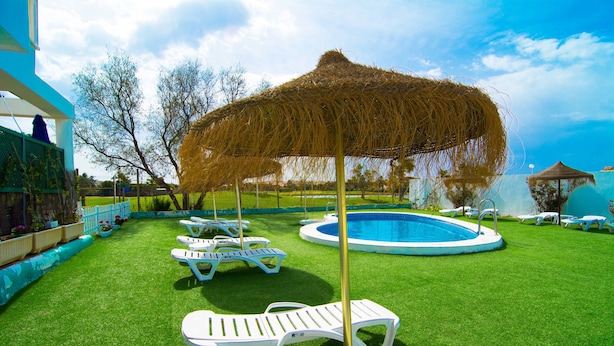 A pool area with white lounge chairs and a thatched umbrella. - Roquetas Beach & Playa Serena Golf (Roquetas de Mar)