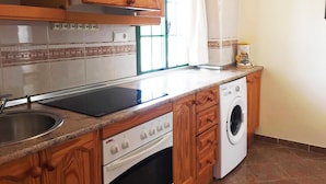 A kitchen with wooden cabinets, a built-in oven, a washing machine, and a coffee maker. - Roquetas Beach & Playa Serena Golf (Roquetas de Mar)