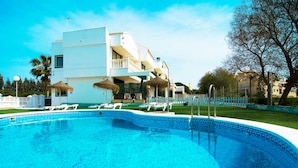 A swimming pool with lounge chairs and umbrellas, surrounded by a white building with balconies and a clear blue sky. - Roquetas Beach & Playa Serena Golf (Roquetas de Mar)