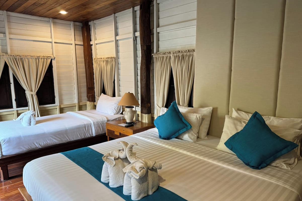 Une chambre d’hôtel avec deux lits, une table de chevet avec une lampe et une fenêtre avec des rideaux.