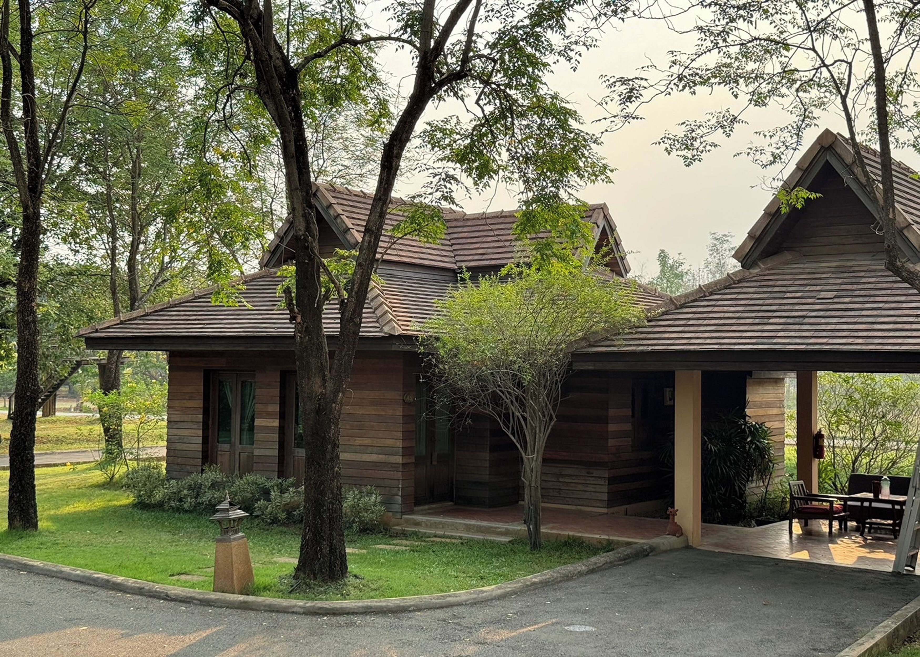 A wooden cabin with a sloped roof, surrounded by trees and a well-maintained lawn.