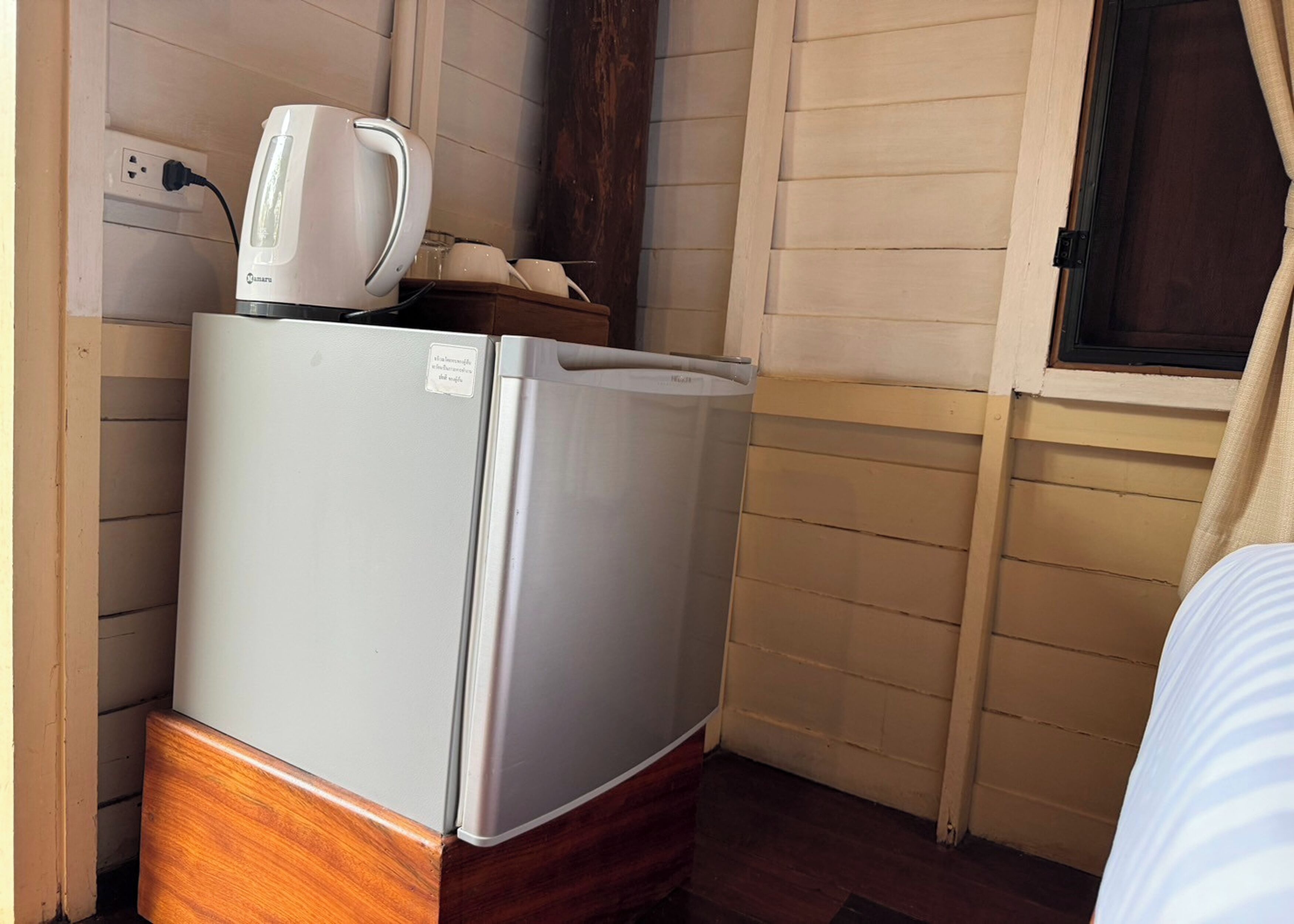 Una kitchenette compacta con un refrigerador blanco, una cafetera y un pequeño armario de madera.