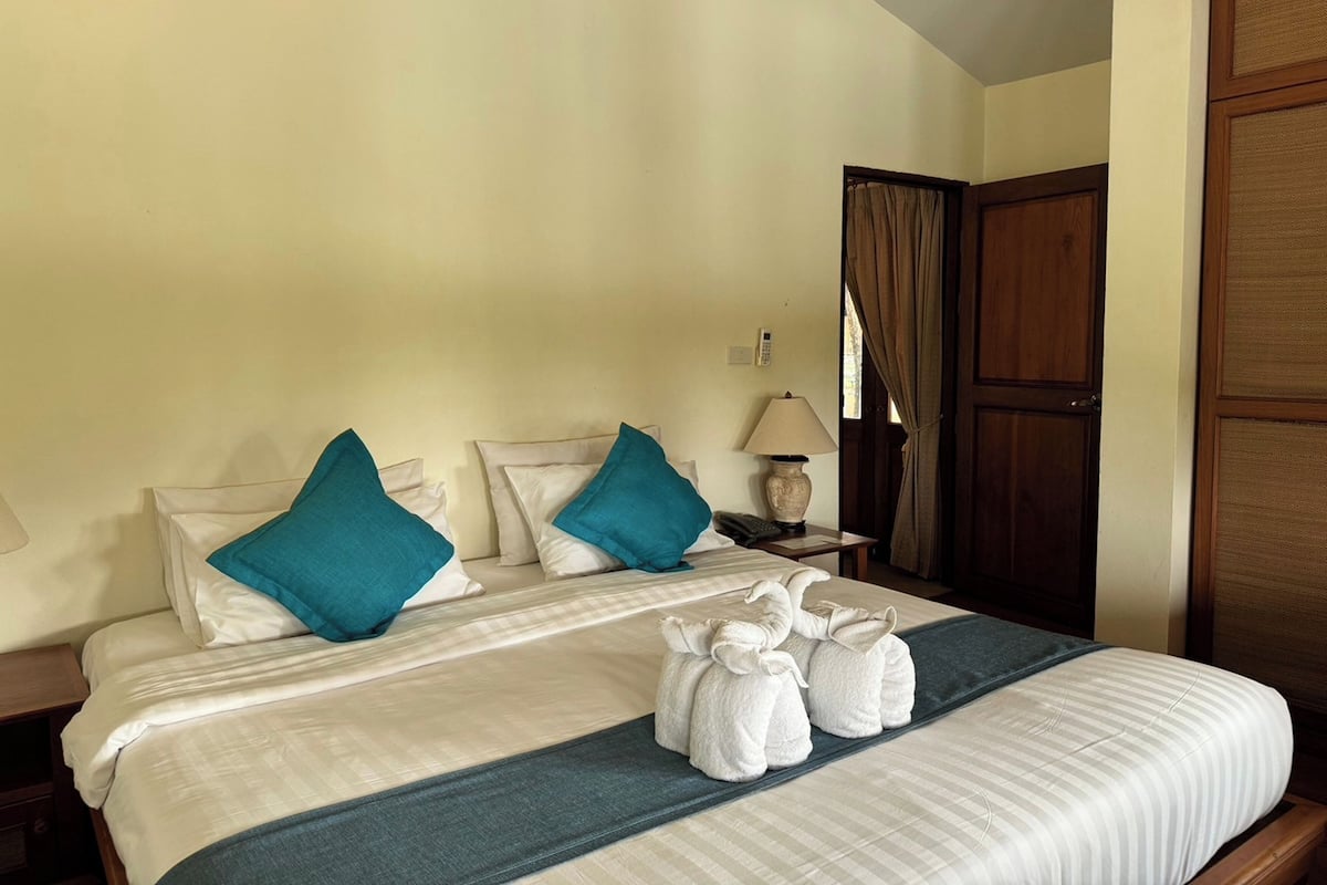 Une chambre d’hôtel avec un grand lit, deux oreillers, une lampe et une porte.