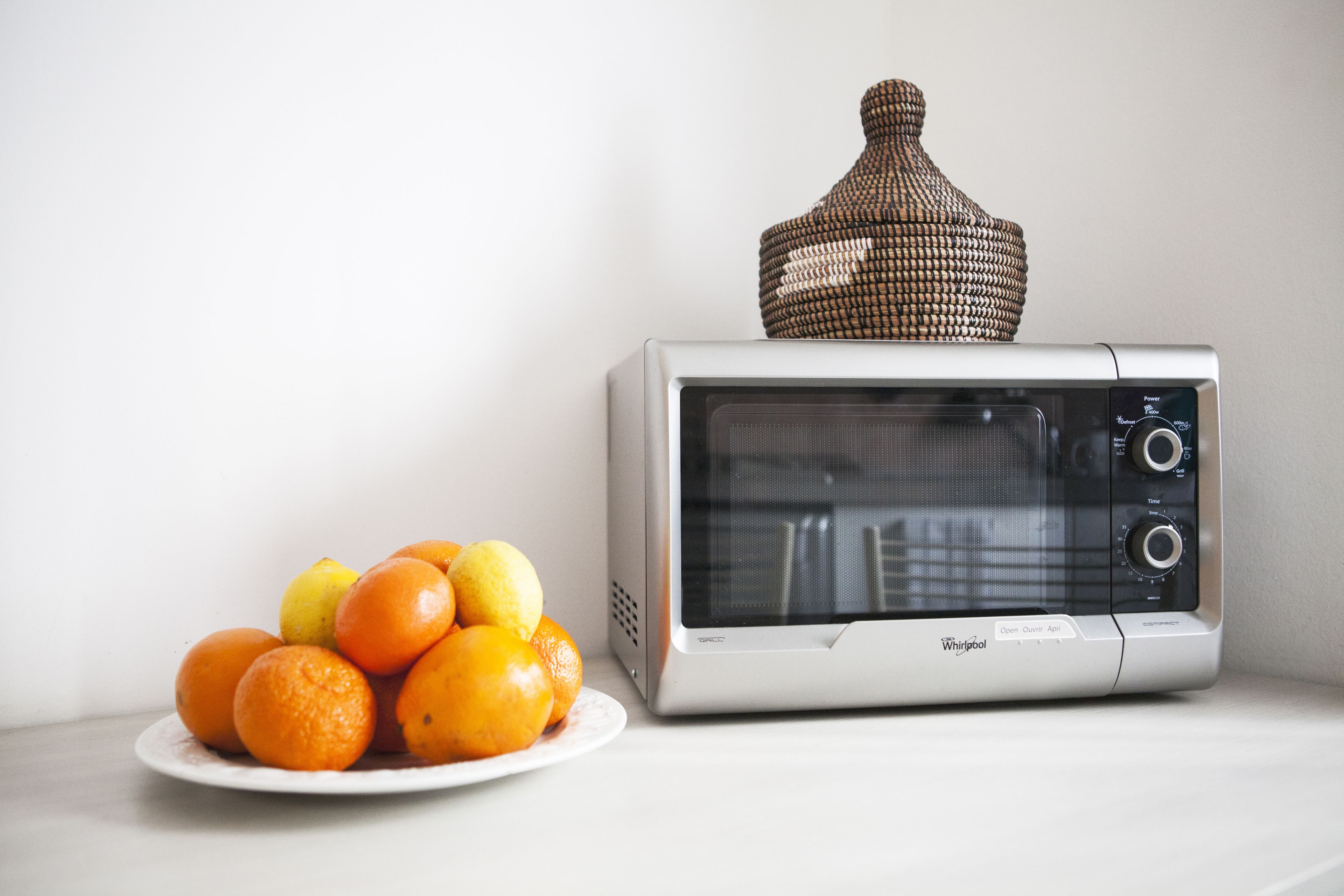 A microwave oven with a plate of oranges and lemons on a white surface.