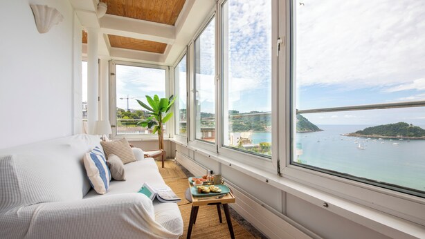 A modern living room with a large window overlooking a scenic bay. - Far Out Inn (San Sebastián)