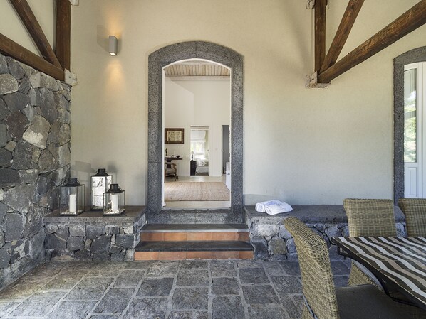 Una entrada con suelo de piedra y una escalera de madera que lleva a un dormitorio.