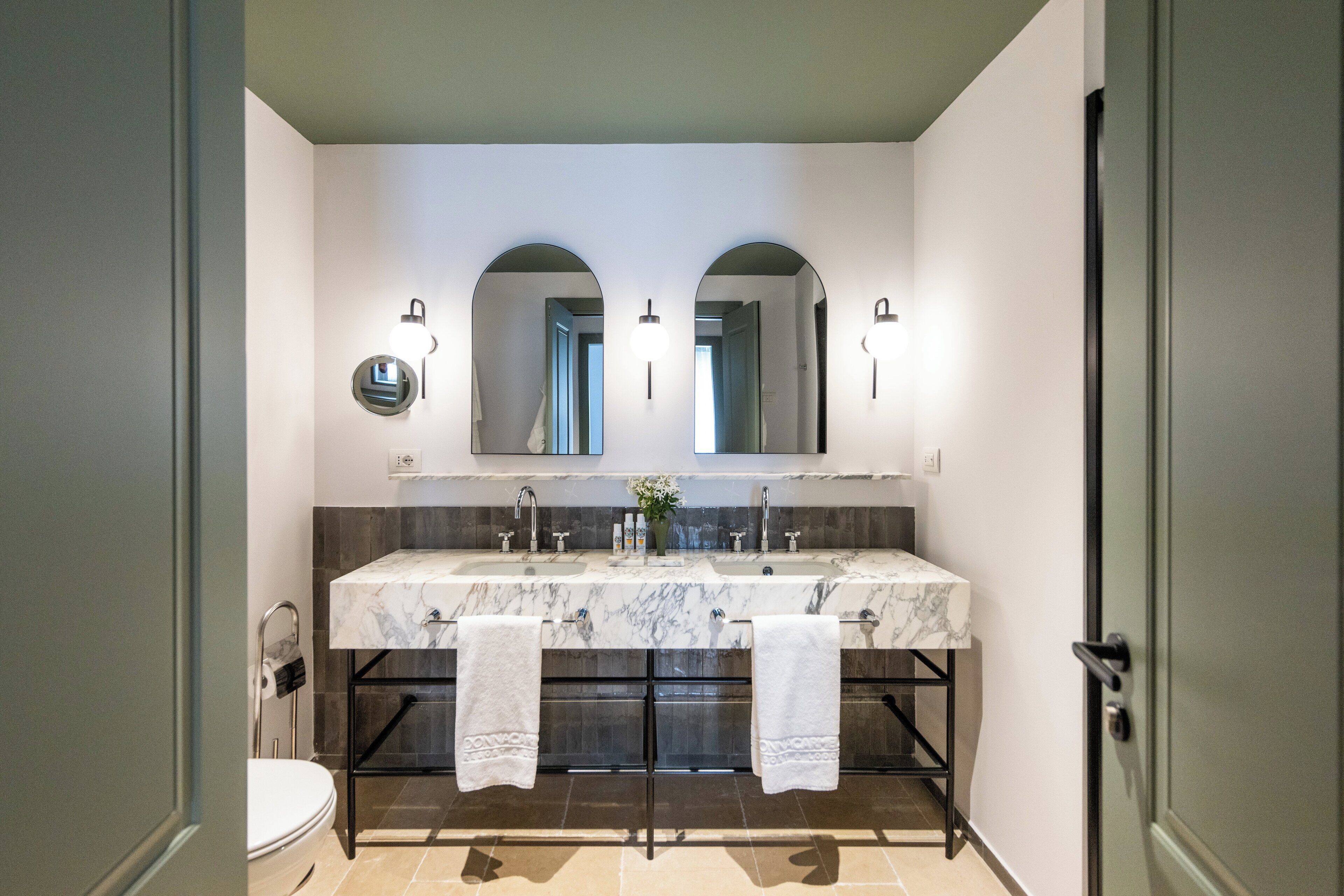 A bathroom with a marble vanity, two sinks, a toilet, and a large mirror.